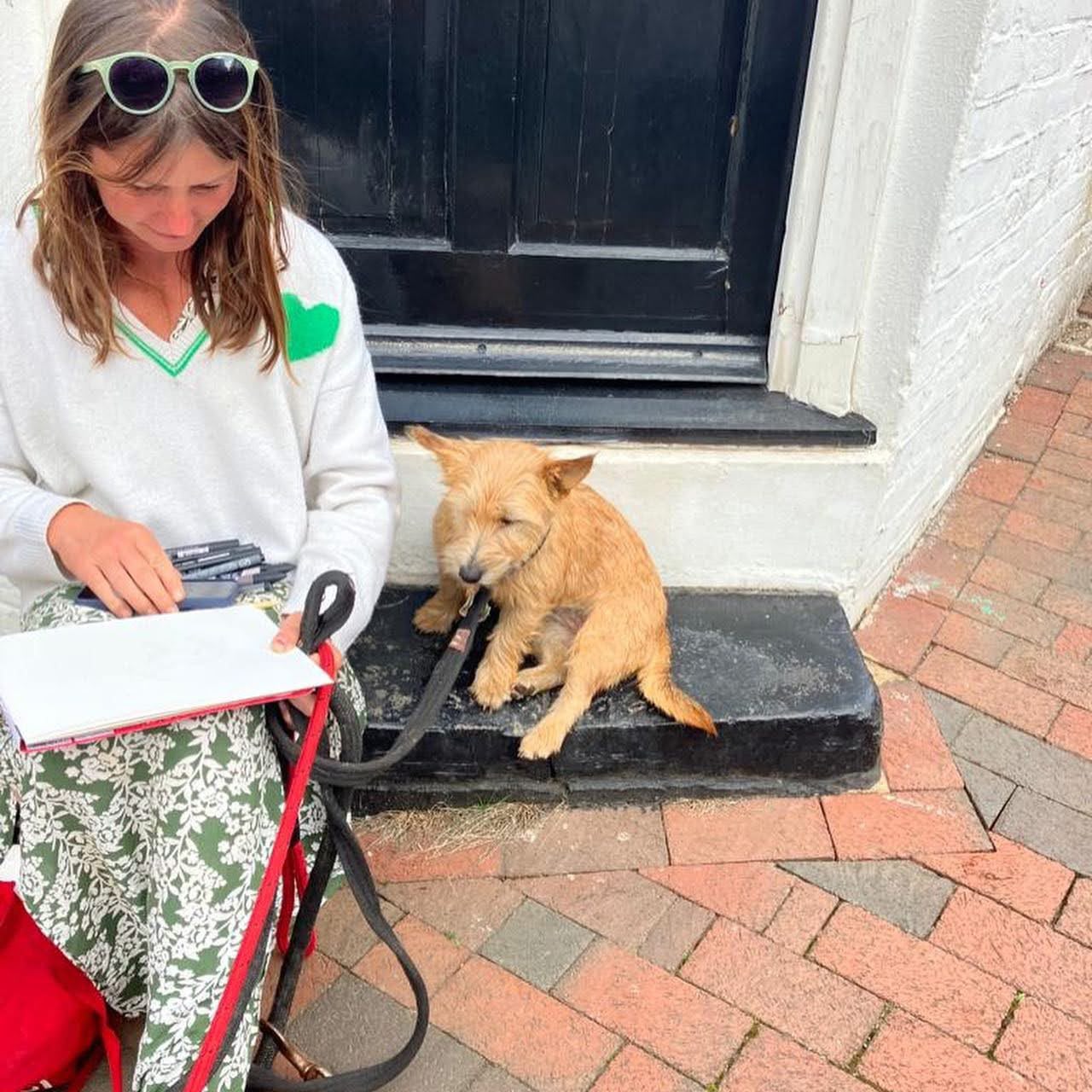 Abbie Hart sketching outdoors with her terrier sitting beside her